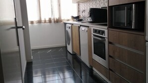 A compact kitchen with a washing machine, microwave, and oven.