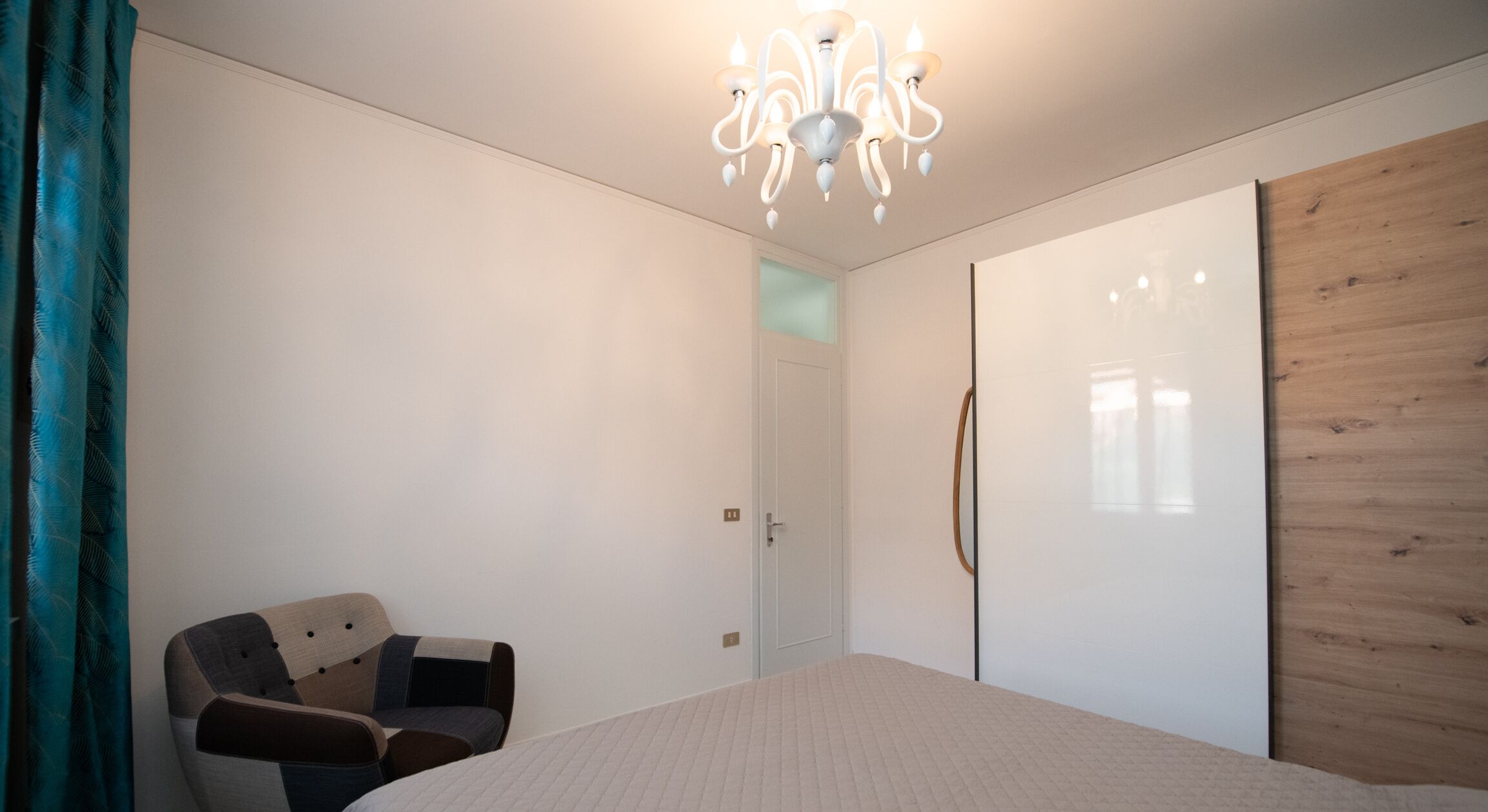 Una camera da letto con un letto, una sedia, un armadio e un lampadario.