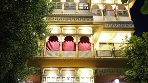 Un immeuble à plusieurs étages, doté de balcons richement décorés et d’une entrée centrale.