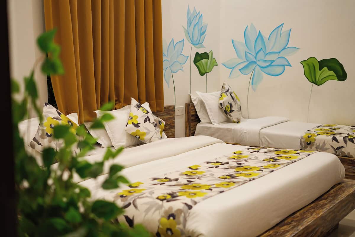 Ein Hotelzimmer mit zwei Betten, einem großen Fenster mit Vorhängen und einer Wandmalerei mit Blumenmotiven.