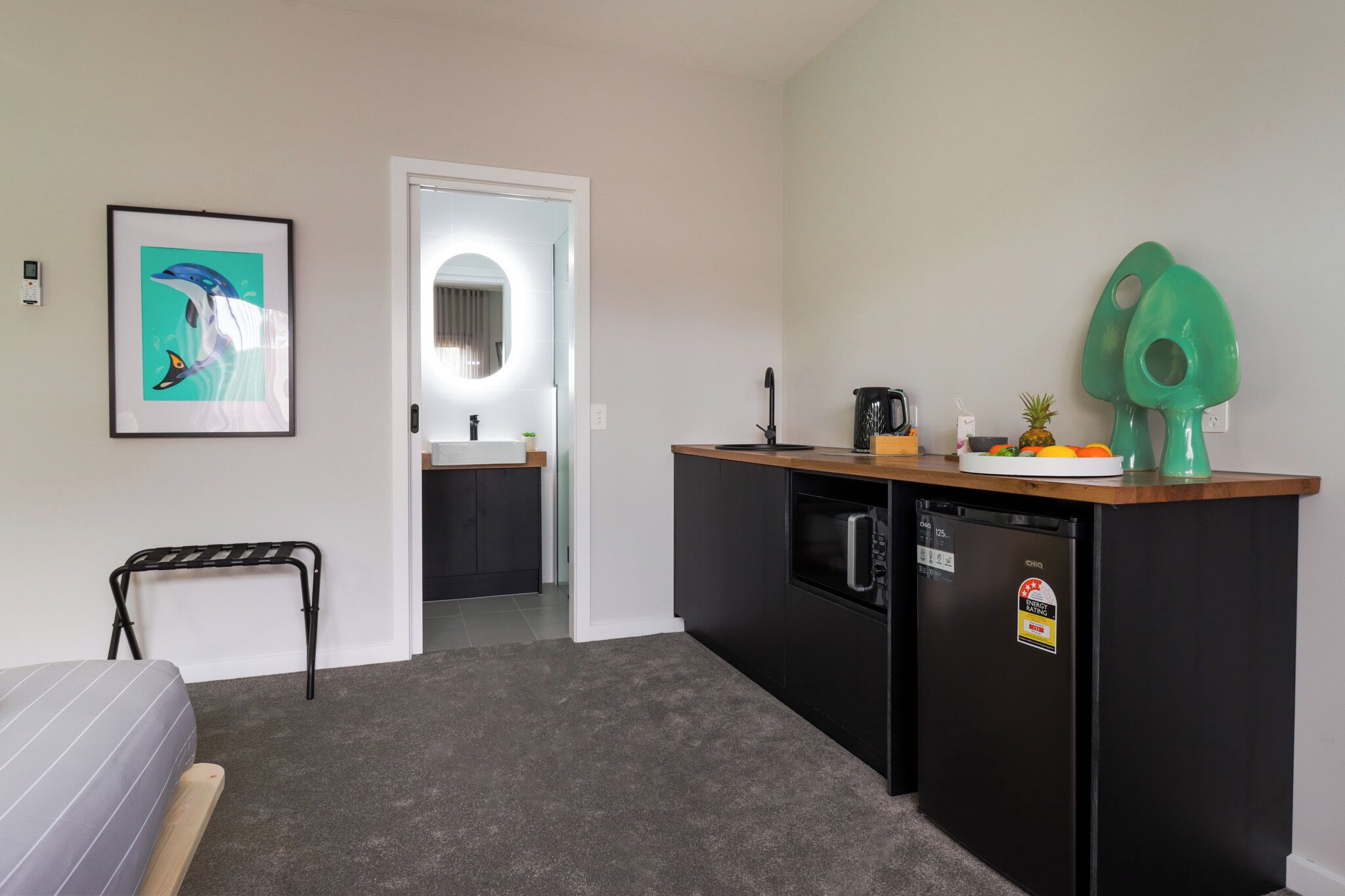 A compact kitchen with a black refrigerator, a wooden countertop, and a small sink.