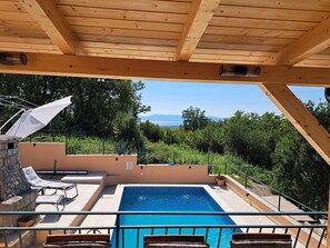 A wooden deck with a pool, lounge chairs, and a view of the landscape. - Villa Tijana with Ocean View and Pool (Omisalj)