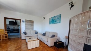 Een moderne woonkamer met een bank, salontafel en een eetgedeelte dat door een open deur zichtbaar is.