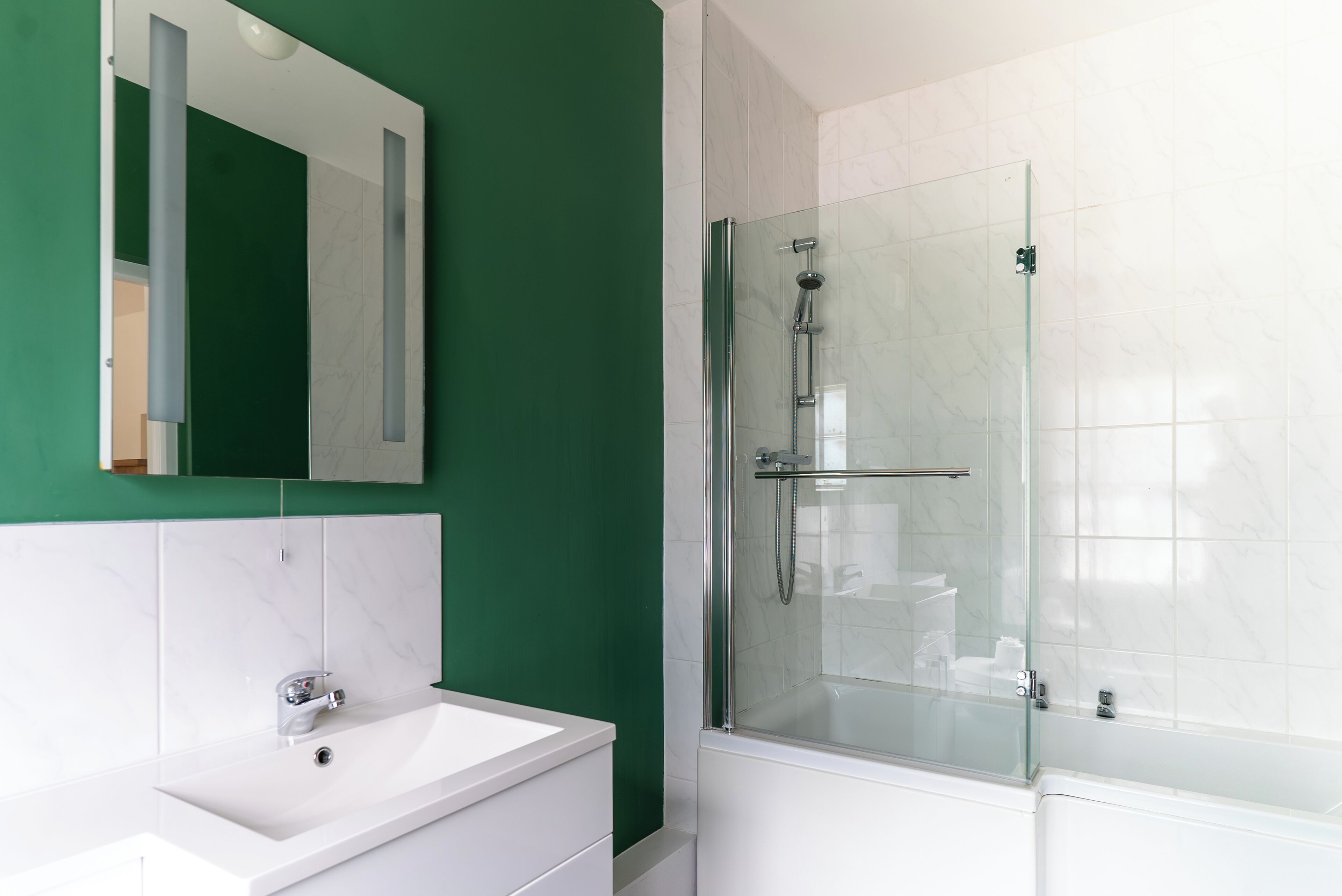 Une salle de bain moderne avec une douche à parois de verre, un lavabo blanc et un miroir au-dessus du lavabo.