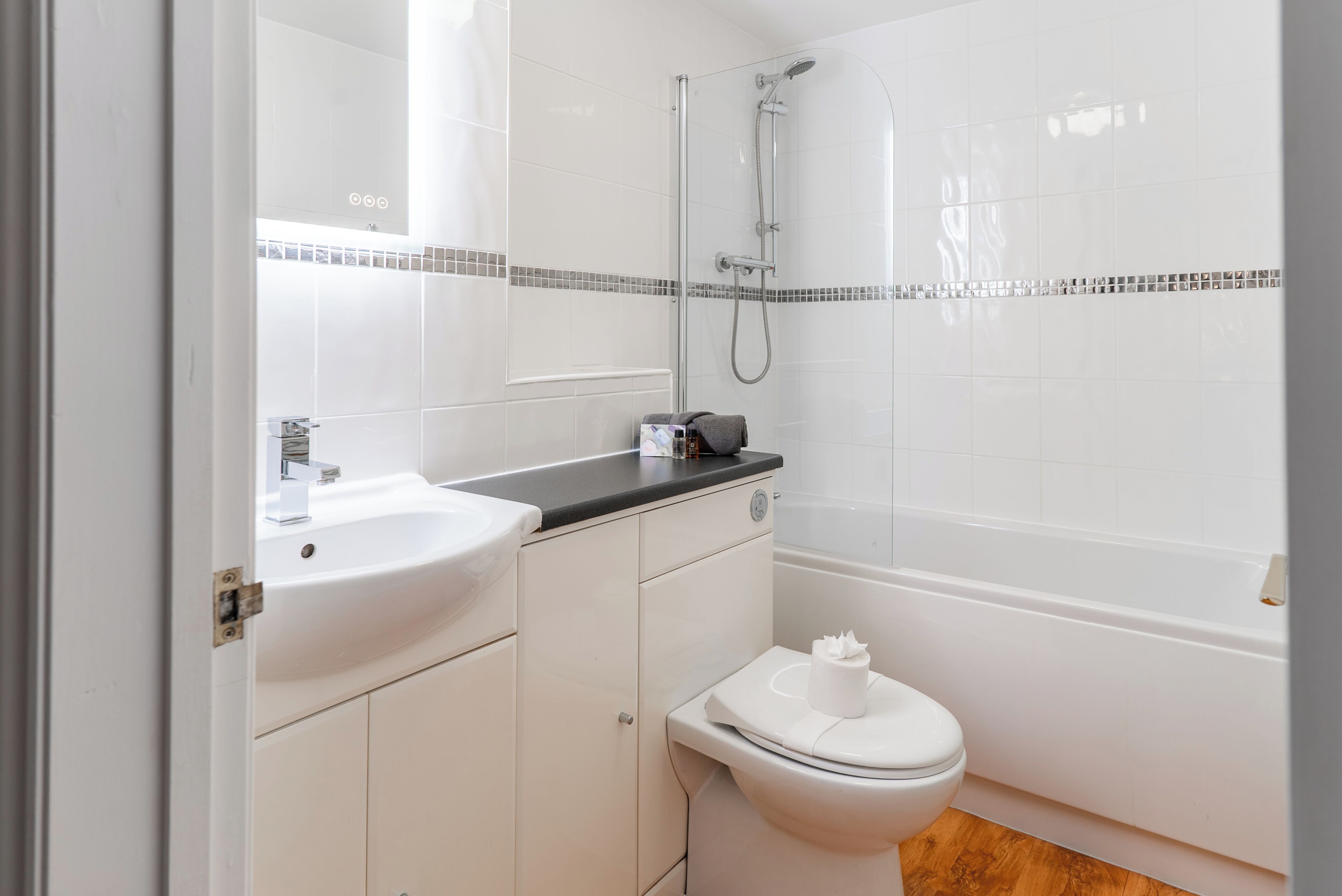 Ein modernes Badezimmer mit Waschbecken, Toilette und Badewanne in Weiß.