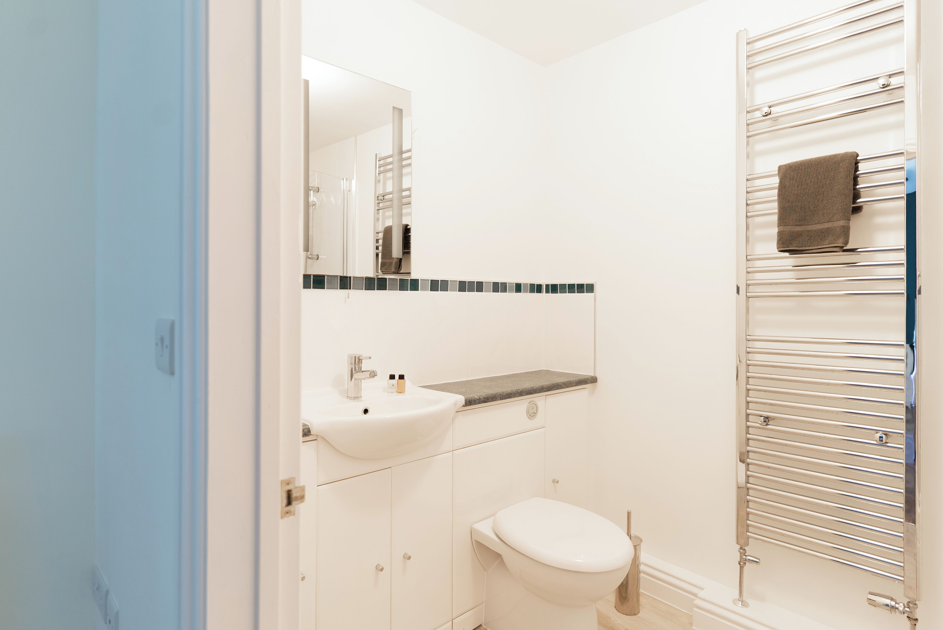 A bathroom with a white sink, a mirror, a toilet, and a towel rack.