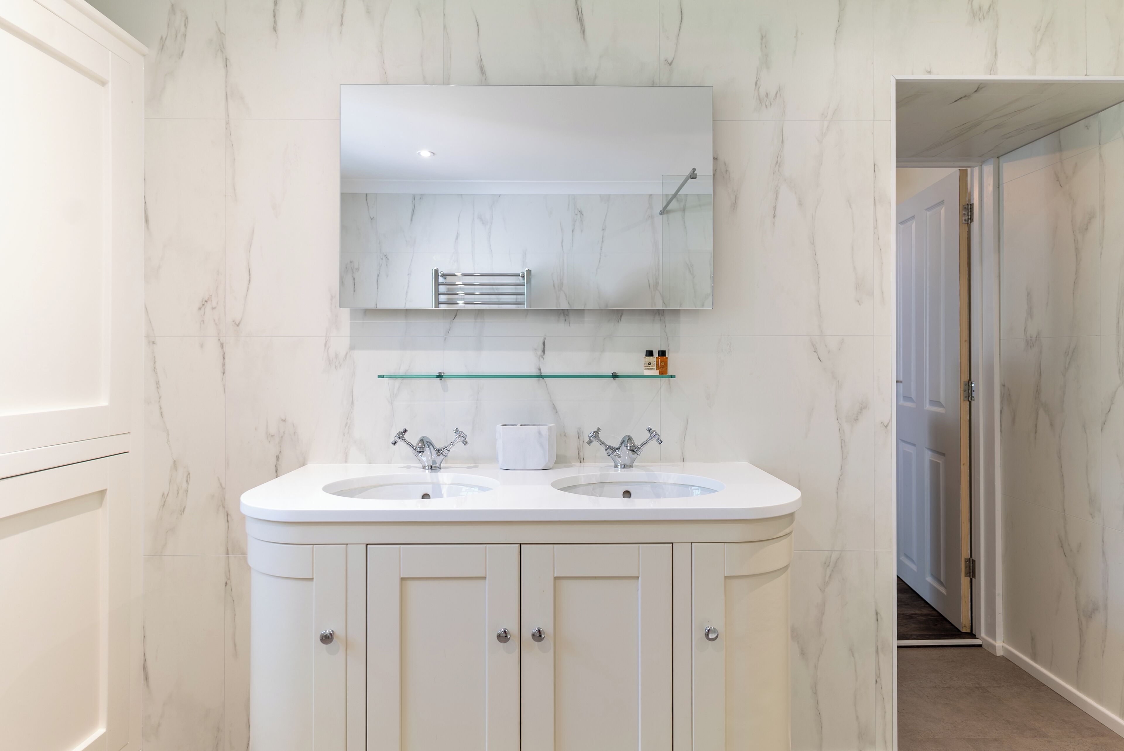 A bathroom with two sinks, a mirror, and a towel rack.