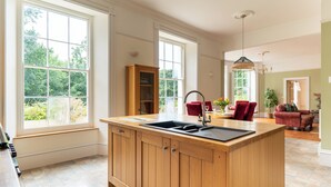 Una cocina amplia con ventanas grandes, una isla de madera con un lavamanos y una silla roja.