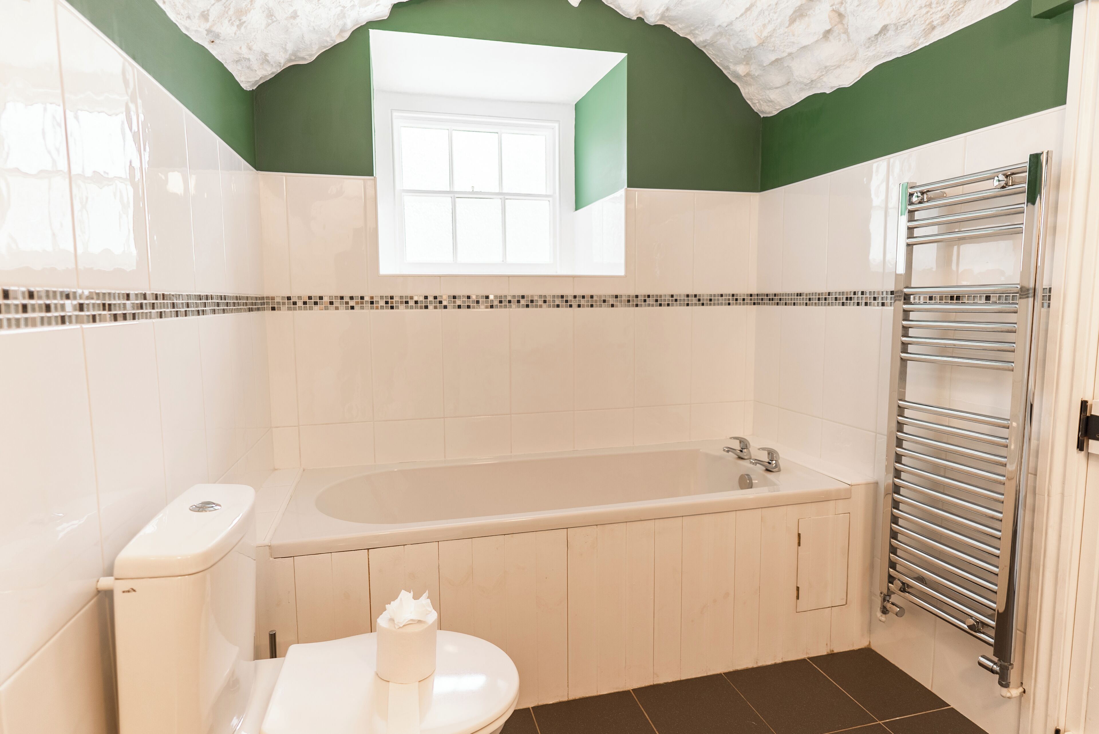 A bathroom with a bathtub, toilet, and a towel rack.