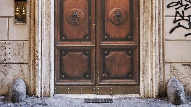 A wooden double door with a glass panel, set in a stone building with a plaque above. - Hidden Treasure-Campo de' Fiori (Rome)