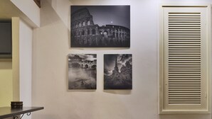 A modern living room with a brown sofa, two striped pillows, and three black-and-white photographs of famous landmarks on the wall. - Hidden Treasure-Campo de' Fiori (Rome)