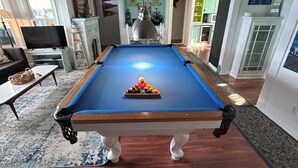 A pool table in a room with a fireplace, a television, and a dining area. - North Coast Cottage. Located on the southern shore of Lake Ontario.  (Ransomville)