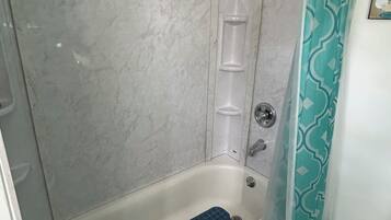 A bathroom with a bathtub, a shower curtain, and a marble wall.