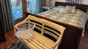 A bedroom with a bed, a wooden bench, a ceiling fan, and a view of the outdoors. - North Coast Cottage. Located on the southern shore of Lake Ontario.  (Ransomville)