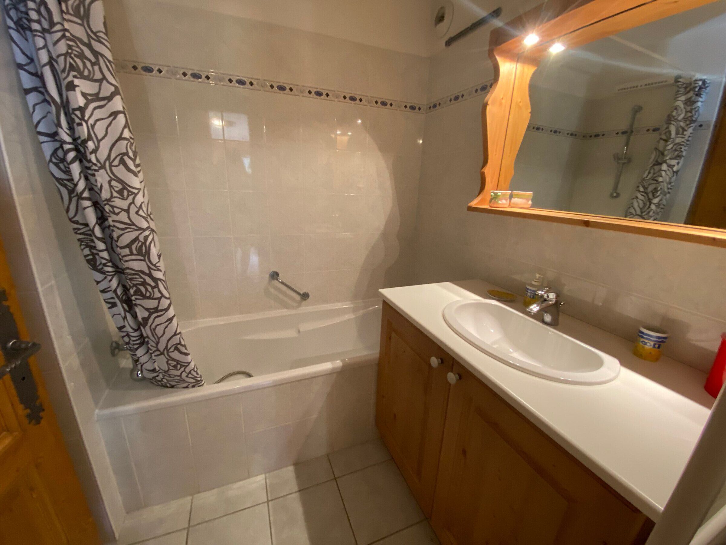 A bathroom with a bathtub, a sink, and a wooden cabinet.