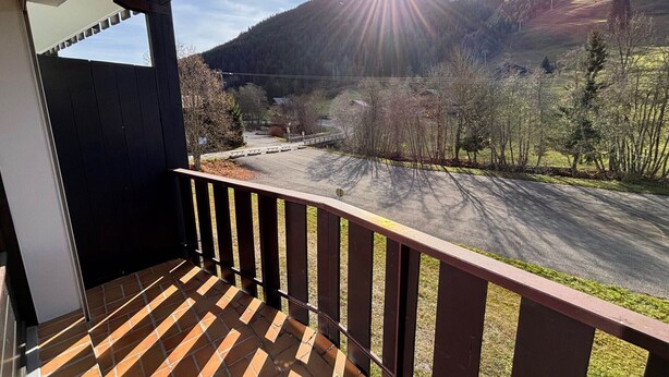 A balcony with a view of a mountain and a parking area.
