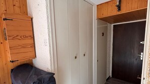 A room with a wooden cabinet, a white wardrobe, and a dark door.