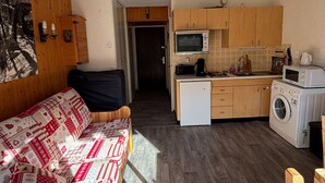 A compact living space with a sofa, kitchenette, and a washing machine.