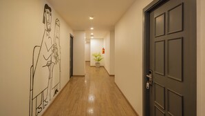 Ein Korridor mit Holzboden, einer dunklen Tür und einer Wand mit abstrakter Kunst.