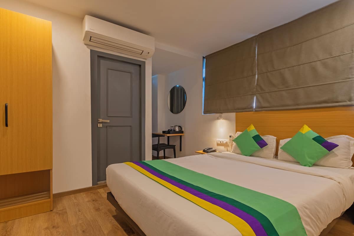 Habitación de hotel con cama, escritorio, armario y ventana con persiana.