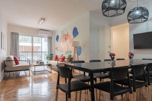 A modern dining area with a glass-top table, black chairs, and a large TV on the wall. - MOT Rentals + Charcas 3000 - 4 Bd Alto Palermo (Buenos Aires)