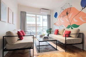 A modern living room with a sofa, a coffee table, and a balcony with a view.