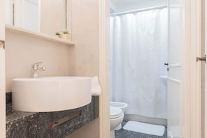 A bathroom with a white sink, a toilet, and a shower curtain.