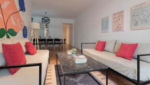Een moderne woonkamer met een bank, salontafel en kunstwerken aan de wanden.