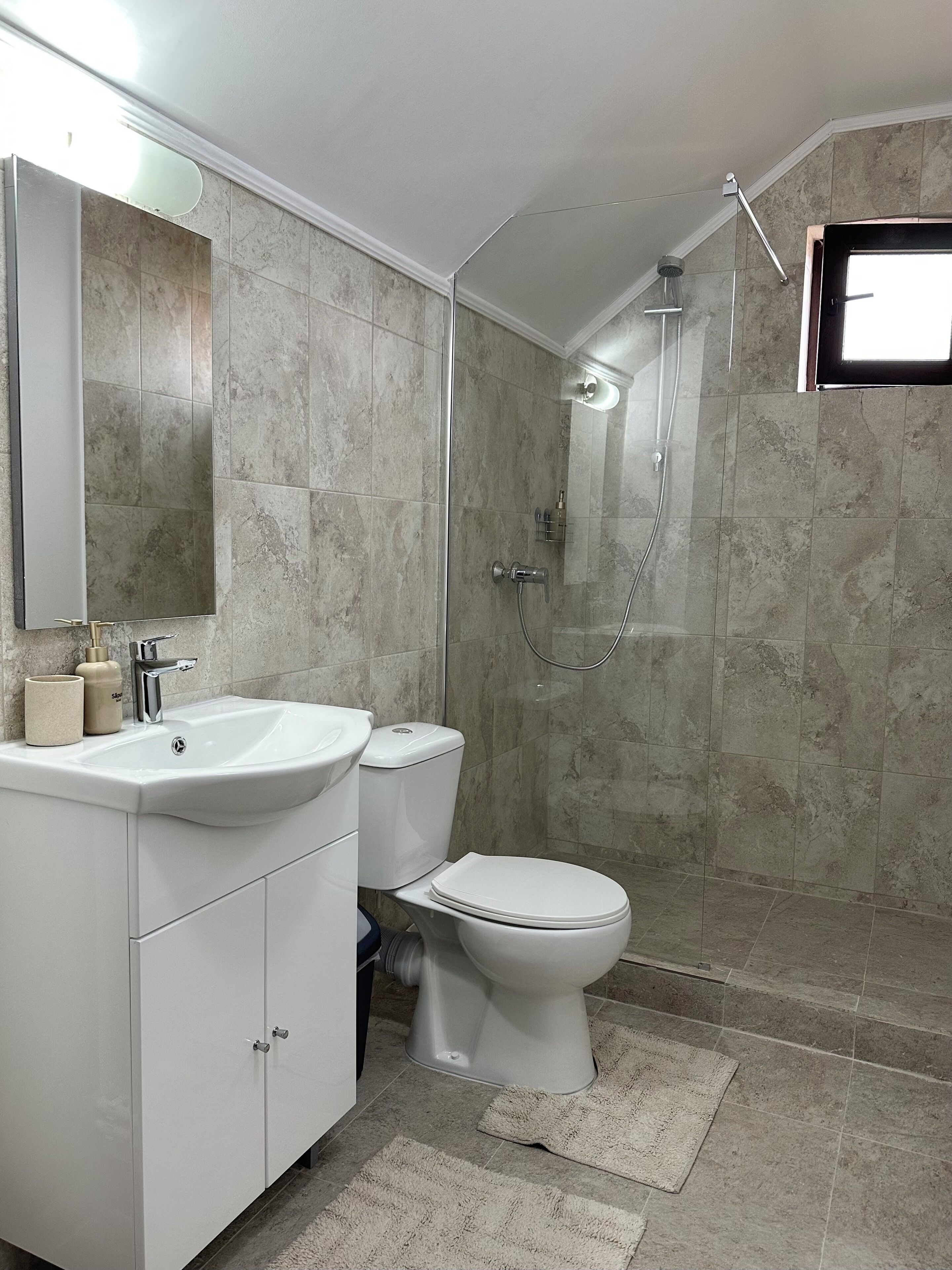 Un bany modern amb un rentapans, vàter i plat de dutxa de color blanc.