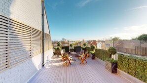 A rooftop terrace with wooden flooring, seating, and a view of the cityscape. - 3-bedroom Penthouse in Knightbridge (London)