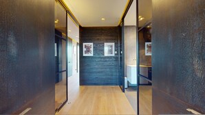 A modern hallway with wooden flooring, glass doors, and framed artwork on the walls. - 3-bedroom Penthouse in Knightbridge (London)