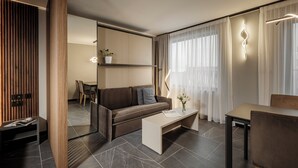 A modern living room with a sofa, coffee table, and dining area. - Isabella Suites (Gzira)