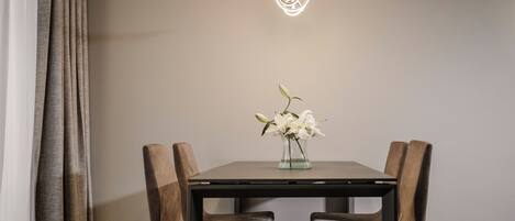 Una mesa de comedor con dos sillas, un jarrón con flores y una lámpara colgante.