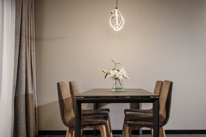 A dining table with two chairs, a vase with flowers, and a pendant light. - Isabella Suites (Gzira)