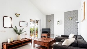 Un salon moderne comprenant un canapé, une table basse, un meuble pour la télévision et des miroirs décoratifs.