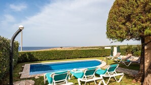 Une piscine avec des chaises longues et vue sur la mer.