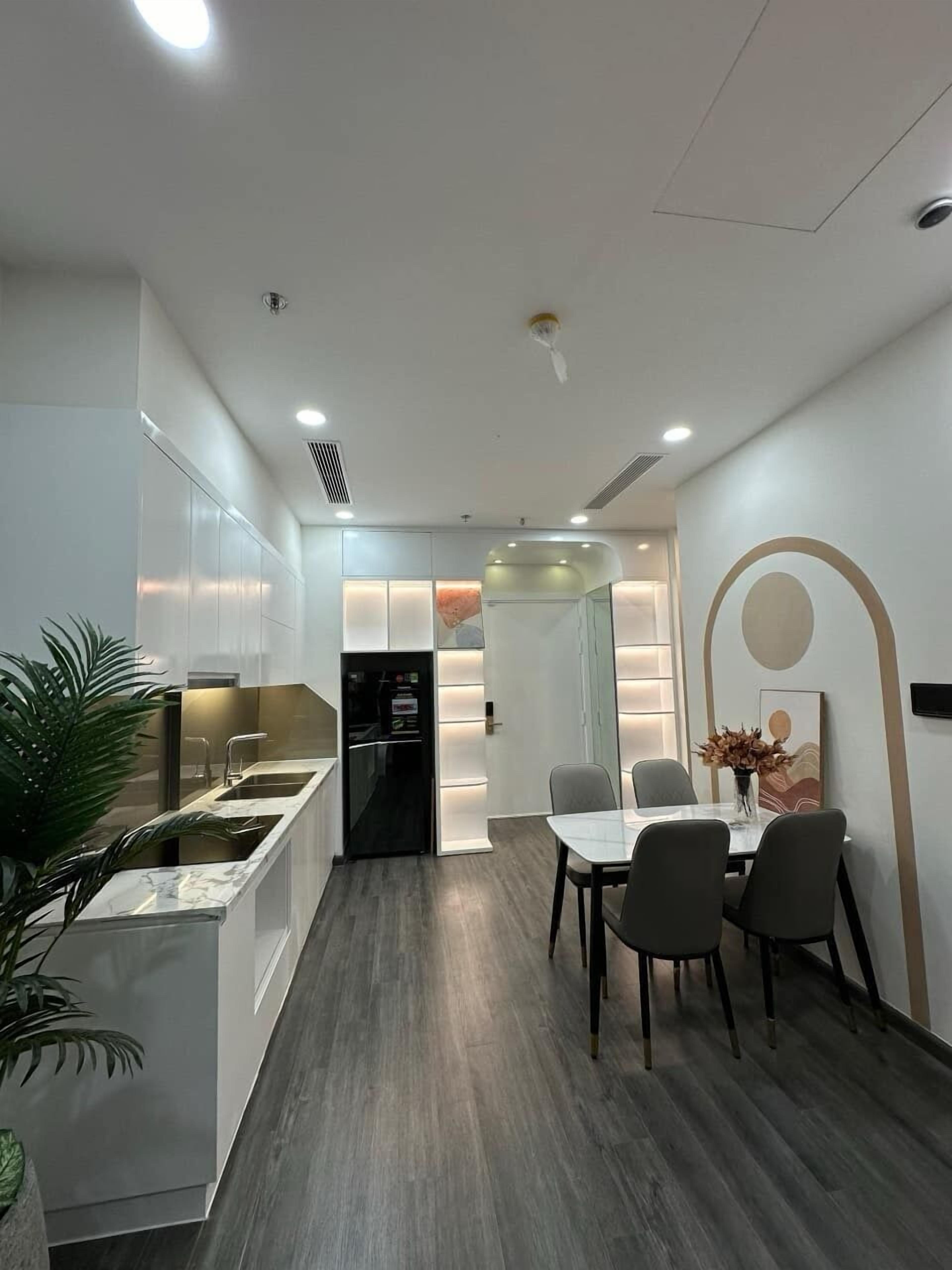 A modern kitchen with a built-in island, a dining area with a table and chairs, and a recessed ceiling light.