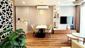 A modern living room with a dining area, a TV mounted on the wall, and a ceiling fan.