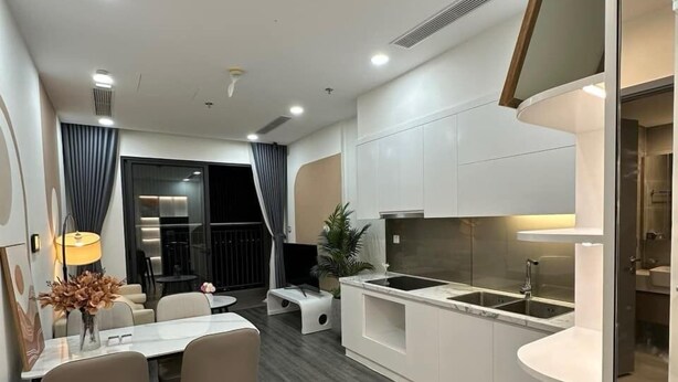 A modern kitchen with white cabinetry, a central island, and a dining area with a table and chairs.