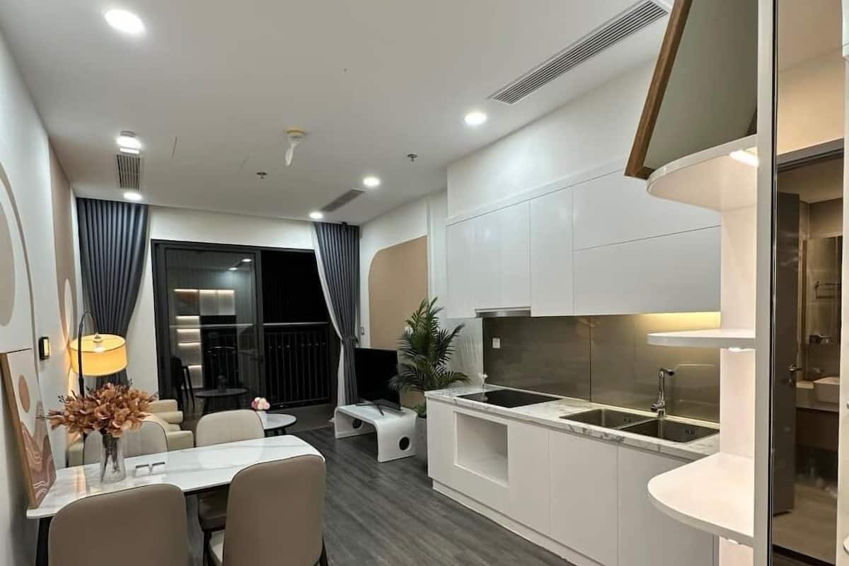 Una cocina moderna con armarios blancos, una isla central y un comedor con mesa y sillas.