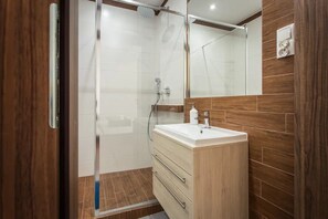 Une salle de bain moderne avec une douche à parois de verre, un meuble-lavabo en bois et un grand miroir.