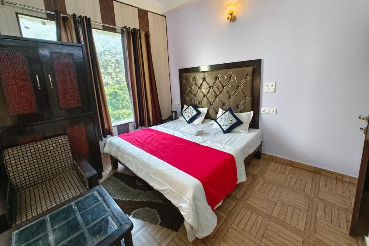 A bedroom with a bed, a TV, a sofa, and a window with curtains.