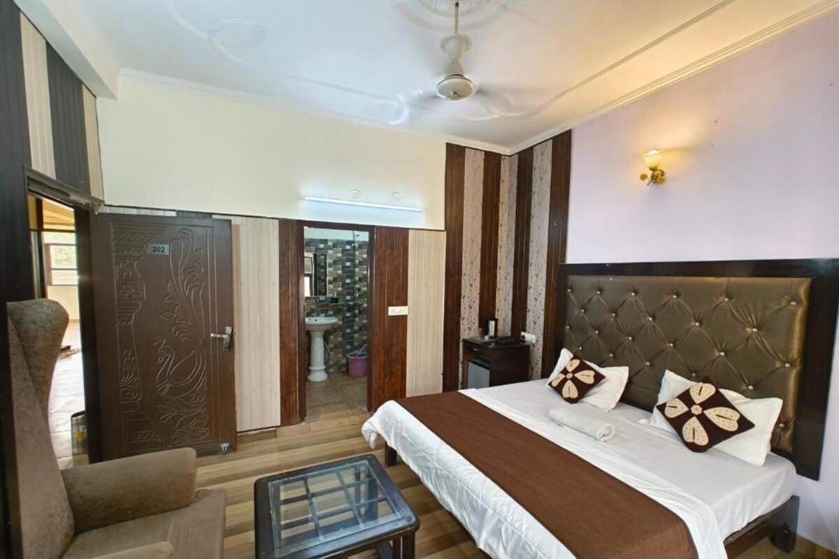 A hotel room with a large bed, a chair, a small table, and a wardrobe.