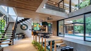 A modern interior with a staircase, dining area, and a poolside view. - La Bandida luxury villa Guiones (Nosara)