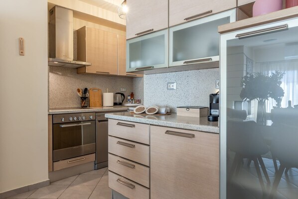 A modern kitchen with stainless steel appliances, wooden cabinets, and a glass-fronted refrigerator. - Zephyrus Cityscape Condo, Apartment (Heraklion)