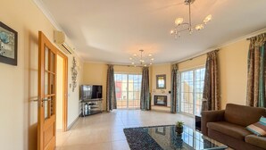 A spacious living room with a sofa, a glass coffee table, a TV, and a fireplace. - Villa Nosredna 5 Bedroom & Pool LES01 (Ayamonte)