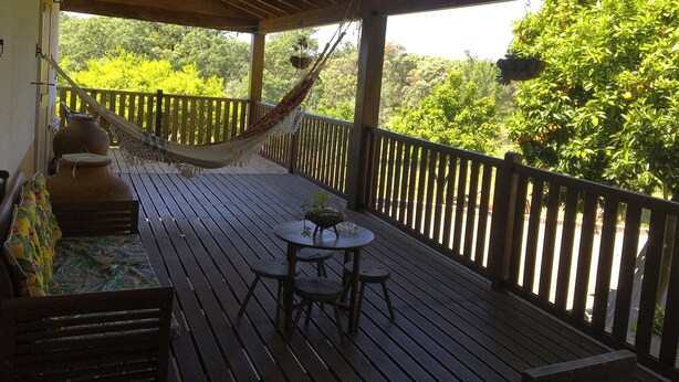 Una terraza de madera con una hamaca, una mesa y una silla.