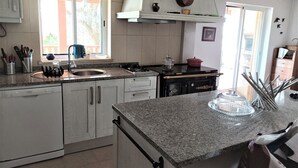 Una cocina con armarios blancos, encimera de granito, estufa y ventana que deja entrar luz natural.