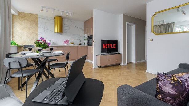 A modern living room with a dining area, a kitchen, and a TV displaying "NETFLIX". - Lumina spacious apartment in Warsaw (Warsaw)