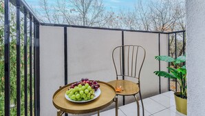 A balcony with a round table, a chair, a potted plant, and a plate of grapes. - Lumina spacious apartment in Warsaw (Warsaw)